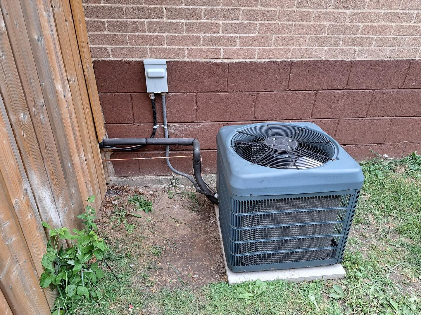 An air-conditioning condenser installed beside a house by Dundas Mechanical (Instagram, January 2025)