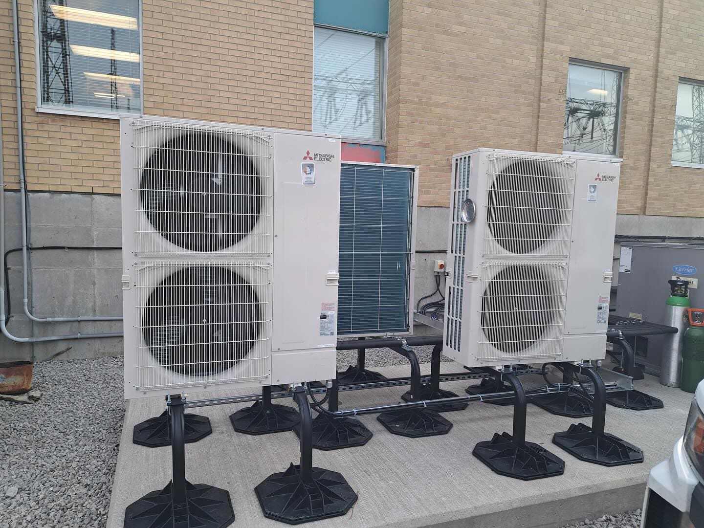 Heat pump outdoor units on stands beside a commercial building, installed by Dundas Mechanical (Instagram, January 2025)